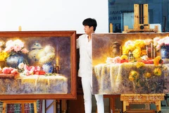 Họa sĩ Đoàn Quốc bên các tác phẩm mầu nước của mình.