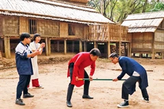Khách tham quan tham gia trò chơi gậy của người dân tộc Mông. 