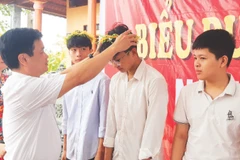 Bí thư Đảng ủy xã Quảng Khê Lê Thanh Tuyên trao vòng nguyệt quế, biểu tượng về thành tích học tập cho học sinh dòng họ Lê.