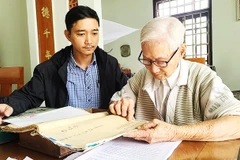 Cụ Hà Thúc Duyên lần dở cuốn địa bạ thời Vua Gia Long. 