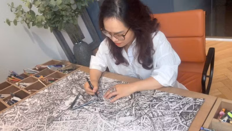 Họa sĩ Hoàng Thị Thu Hà miệt mài bên tác phẩm.