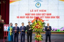 Đồng chí Đỗ Văn Chiến tặng hoa, chúc mừng các thầy giáo, cô giáo và toàn thể sinh viên Học viện Tài chính. (Ảnh: SƠN TÙNG)