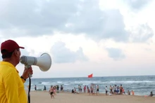 Thành viên đội cứu hộ trên bãi biển Nhật Lệ nhắc nhở du khách tuân thủ quy định để tắm biển an toàn. (Ảnh: minh họa)