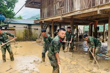 Chiến sĩ các đơn vị thuộc Bộ Chỉ huy quân sự tỉnh Điện Biên giúp người dân xã Mường Pồn thu dọn nhà cửa, dọn dẹp vệ sinh ổn định cuộc sống sau lũ quét. 