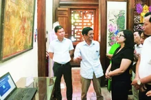 Nghệ nhân Lê Đình Nghiên (thứ hai từ trái sang) giới thiệu về tranh Hàng Trống trong triển lãm Phục hồi tại đình Nam Hương, quận Hoàn Kiếm.