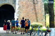 Khách du lịch nước ngoài theo tour tham quan Hà Nội bằng xe đạp tại thành Cửa Bắc trên phố Phan Đình Phùng. (Ảnh: T.LINH)