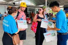 Đoàn công tác huyện Cô Tô tuyên truyền và cung cấp túi giấy thay thế túi nilon cho du khách trong giai đoạn đầu thí điểm. (Ảnh: Trung tâm Thông tin-Văn hóa huyện Cô Tô) 