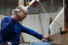 Nghệ nhân Lê Đăng Toản bên khung cửi truyền thống, chuyên dệt lụa the thủ công. (Ảnh THẾ ĐẠI)