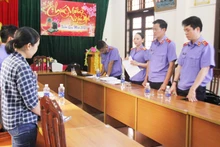 Phan Thị Anh (bên trái) đang nghe cơ quan chức năng tống đạt quyết định khởi tố.