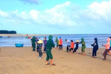 Bộ đội Biên phòng và người dân hỗ trợ anh Phạm Thanh Huân kéo thuyền đánh cá bị nạn vào bờ. 