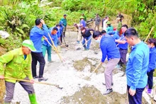 Cán bộ, hội viên các tổ chức giúp nhân dân thôn Bản Lằn trộn bê-tông làm đường giao thông thôn, bản.