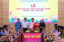 Ông Phạm Thiện Nghĩa trao quyết định, Bí thư Huyện ủy Tháp Mười Trần Thị Quý tặng hoa chúc mừng ông Đoàn Thanh Bình. (Ảnh: THÀNH NHƠN)