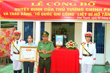 Đại tá Nguyễn Văn Hiểu, Giám đốc Công an tỉnh Đồng Tháp trao Bằng “Tổ quốc ghi công” cho vợ Liệt sĩ Hồ Tấn Dương.