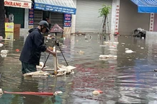 Nhân viên Công ty TNHH MTV Công trình đô thị Nam Định vớt rác trôi nổi, tiêu thoát nước úng ngập trên đường Trần Hưng Đạo, thành phố Nam Định.