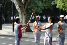 Hai thành viên rước đuốc trao truyền lửa thiêng ASIAD 19. (Ảnh: people.com.cn)