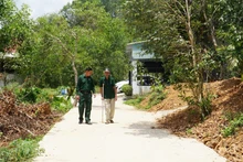 Hai cha con ông Bùi Văn Tượng đi trên con đường mới từ một phần đất gia đình đóng góp.