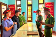 Nguyễn Quốc Trung, Giám đốc Công ty TNHH Thạch Phú Hưng (áo đen, thứ 2 từ trái sang) nghe đọc lệnh khởi tố. (Ảnh: Công an cung cấp)