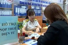 Cán bộ ngành thuế hướng dẫn hộ kinh doanh nộp thuế điện tử. (Ảnh minh họa)