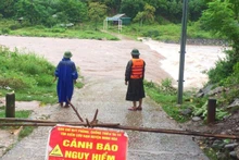 Lực lượng chức năng đặt biển cảnh báo và cử tổ công tác cảnh giới đoạn đường ngập sâu ở huyện Minh Hóa.