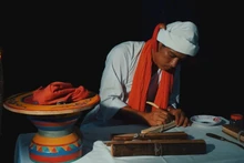 Phó Cả sư Nại Cao Liêm đang thực hiện công đoạn khắc chữ trên lá buông. (Ảnh: NGỌC XIÊM)
