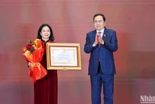 Chủ tịch Quốc hội Trần Thanh Mẫn trao Huân chương Lao động hạng Nhất và tặng hoa chúc mừng đồng chí Lê Thị Nguyệt. (Ảnh: Duy Linh)