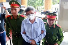 Lực lượng chức năng dẫn giải bị cáo Nguyễn Thanh Long (cựu Bộ trưởng Y tế) đến phiên tòa. (Ảnh: Phạm Kiên/TTXVN)