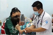 Bác sĩ Bệnh viện Nhi đồng 1 TP Hồ Chí Minh thăm khám cho trẻ mắc tay chân miệng. (Ảnh: THẾ ANH)