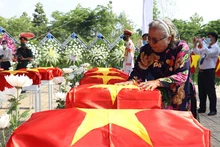 Bà Thân Thị Vân xúc động bên hài cốt đồng đội trong lễ truy điệu tại Nghĩa trang liệt sĩ huyện Nhơn Trạch (Đồng Nai).