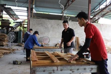 Anh Phùng Bình Minh (người đứng giữa) hướng dẫn công nhân sản xuất gỗ ván thanh xuất khẩu.