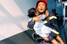 Lực lượng cứu hộ bế một em bé ra ngoài hiện trường vụ cháy.