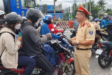 Trạm Cảnh sát giao thông Tân Túc phát tờ rơi tuyên truyền và tổ chức tặng nước suối, khăn lạnh cho người dân về quê nghỉ lễ.