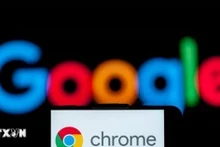 Biểu tượng Chrome trên màn hình điện thoại và biểu tượng Google (phía sau). (Ảnh: Getty Images/TTXVN)