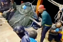 Thanh niên dùng cây gỗ đội nón màu cam đánh người trên tàu. (Ảnh cắt từ clip). 
