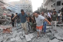 Chuyển thi thể nạn nhân sau các cuộc không kích của Israel xuống Dải Gaza. Ảnh: IRNA/TTXVN