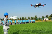 Kỹ sư của Công ty cổ phần Tập đoàn Lộc Trời trình diễn phun thuốc bảo vệ thực vật trên ruộng lúa bằng thiết bị bay không người lái. (Ảnh CÔNG MẠO)