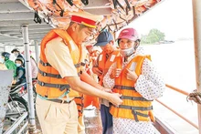 Cảnh sát đường thủy Công an thành phố Cần Thơ hướng dẫn người dân mặc áo phao đúng cách, bảo đảm an toàn mùa mưa lũ. (Ảnh DUY LINH)