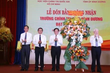Nguyên Chủ tịch nước Nguyễn Minh Triết (bên phải) trao tặng lẵng hoa chúc mừng Trường Chính trị tỉnh Bình Dương đạt chuẩn mức 1. 