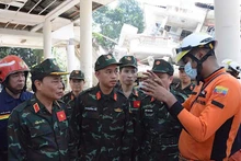 Trưởng đoàn lực lượng cứu hộ cứu nạn Việt Nam trao đổi nhanh cùng đại diện Cục Phòng cháy chữa cháy, Bộ Nội vụ Myamar, thống nhất về nghiệp vụ, nội dung, phương pháp và cách thức tổ chức tìm kiếm cứu nạn. (Ảnh: Báo Quân đội nhân dân từ Myanmar)