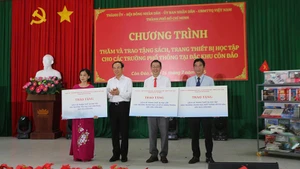 Đồng chí Nguyễn Văn Nên, Ủy viên Bộ Chính trị, Bí thư Thành ủy Thành phố Hồ Chí Minh trao bảng tượng trưng tặng sách và thiết bị học tập cho 3 trường tại Côn Đảo (Ảnh Ban tổ chức).