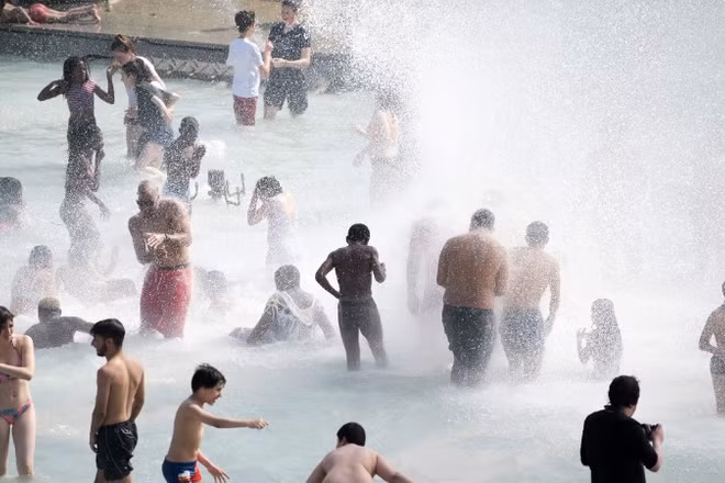 Người dân tránh nóng tại đài phun nước ở Paris, Pháp. Ảnh: THX/TTXVN