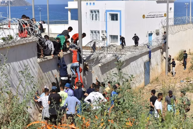Người di cư trèo qua hàng rào biên giới để vào vùng lãnh thổ Ceuta của Tây Ban Nha từ thành phố Fnideq, Maroc. (Ảnh: THX/TTXVN)