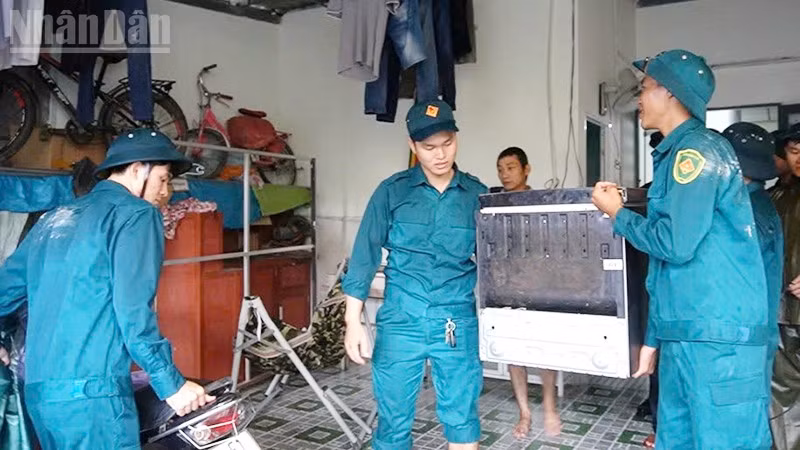Lực lượng dân phòng hỗ trợ người dân vùng nguy cơ ngập lụt kê cao đồ đạc.