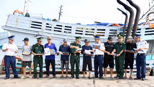 Bộ đội biên phòng Thành phố Hồ Chí Minh và Cảnh sát biển 3 phát tờ rơi tuyên truyền phòng chống IUU tại cảng cá Cát Lở. (Ảnh: Cảnh sát biển cung cấp) 