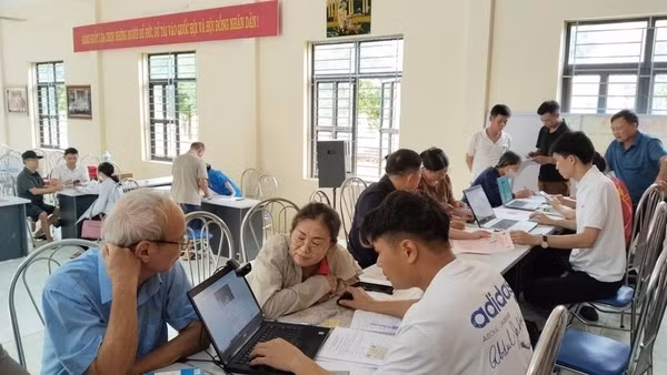 Cán bộ thôn Hồng Kỳ, xã Trung Giã (Hà Nội) hướng dẫn người dân cách sử dụng ứng dụng eTax Mobile, iHanoi và khai báo làm sạch dữ liệu đất đai. (Ảnh: LÊ TRƯỜNG) 