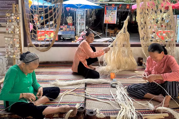 Nghệ nhân Lê Thị Kề (trái) hướng dẫn cách đan võng ngô đồng.