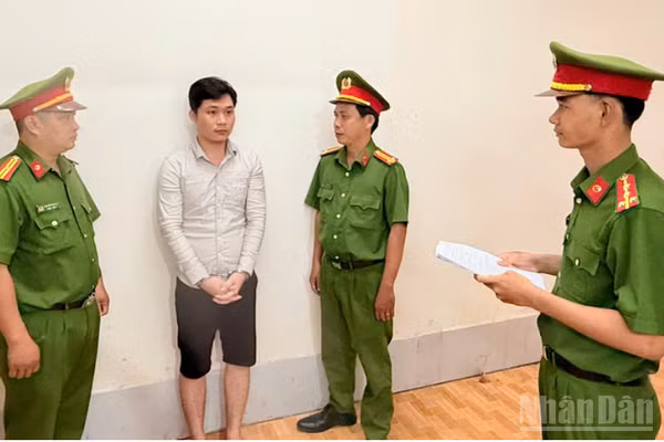 Điều tra viên thi hành lệnh bắt bị can để tạm giam đối với Huỳnh Thanh Huy. (Ảnh: Công an cung cấp)