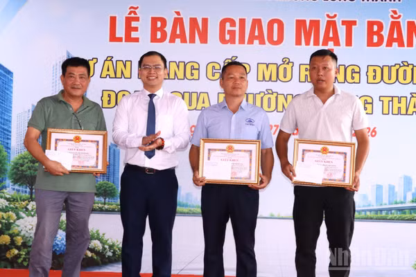 Chủ tịch Ủy ban nhân dân phường Long Thành Lê Hoàng Sơn trao khen thưởng cho các hộ dân tiêu biểu trong bàn giao mặt bằng Dự án nâng cấp, mở rộng đường 25B. (Ảnh: THIÊN VƯƠNG)