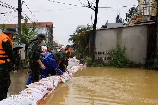 Lực lượng bộ đội hỗ trợ đắp đê bao ngăn nước khu dân cư ven sông Bùi. (Ảnh: TTXVN)