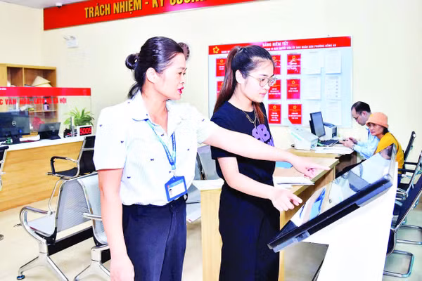 Cán bộ công chức Trung tâm Phục vụ hành chính công phường Hồng An, thành phố Hải Phòng hướng dẫn người dân thực hiện nộp hồ sơ trực tuyến. (Ảnh TRUNG KIÊN)