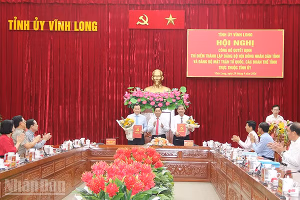 Đại diện các Đảng bộ Hội đồng nhân dân, Mặt trận Tổ quốc, các đoàn thể tỉnh Vĩnh Long nhận quyết định tại hội nghị. (Ảnh: MINH KHỞI)